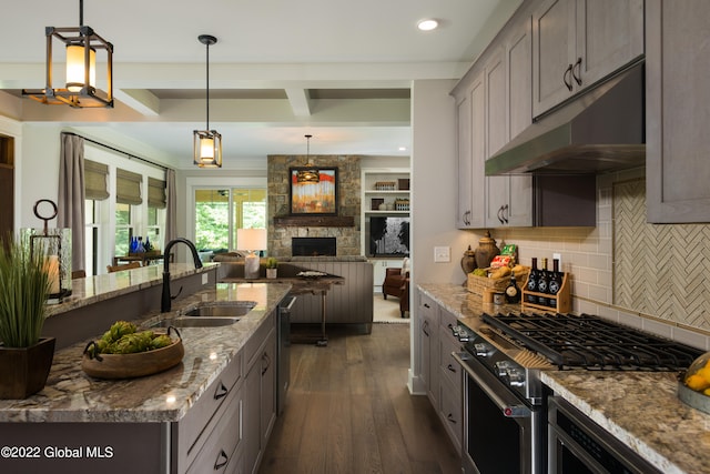 kitchen featuring light stone countertops, sink, backsplash, decorative light fixtures, and appliances with stainless steel finishes