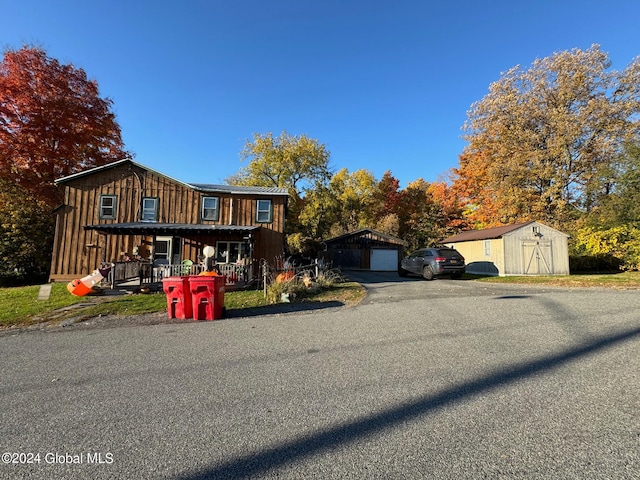 view of front of house featuring a porch, a storage unit, and a garage