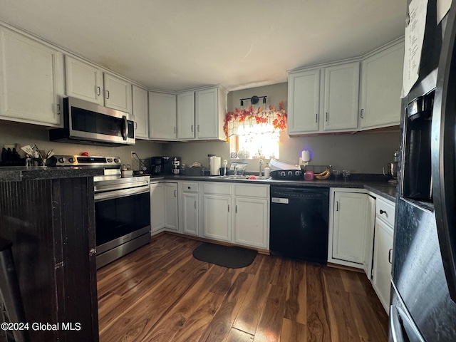 kitchen featuring dark wood finished floors, appliances with stainless steel finishes, dark countertops, a sink, and white cabinetry
