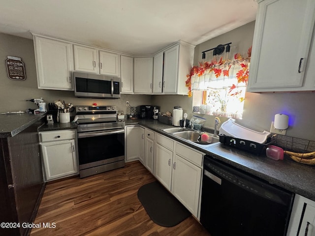 kitchen with dark wood-style flooring, dark countertops, stainless steel appliances, and a sink