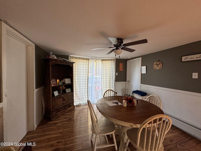 dining space featuring dark wood-style flooring, a wainscoted wall, and a ceiling fan