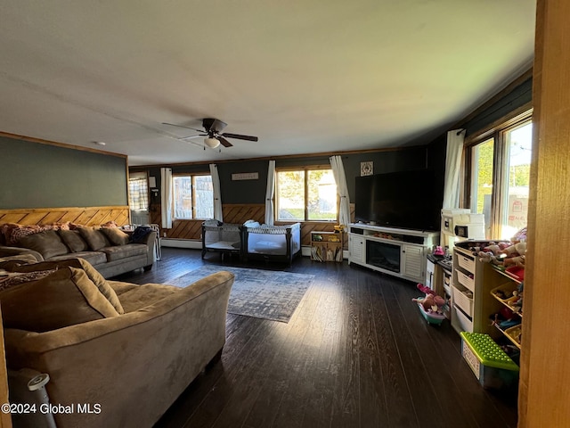 living room featuring wood walls, ceiling fan, baseboard heating, and dark hardwood / wood-style flooring