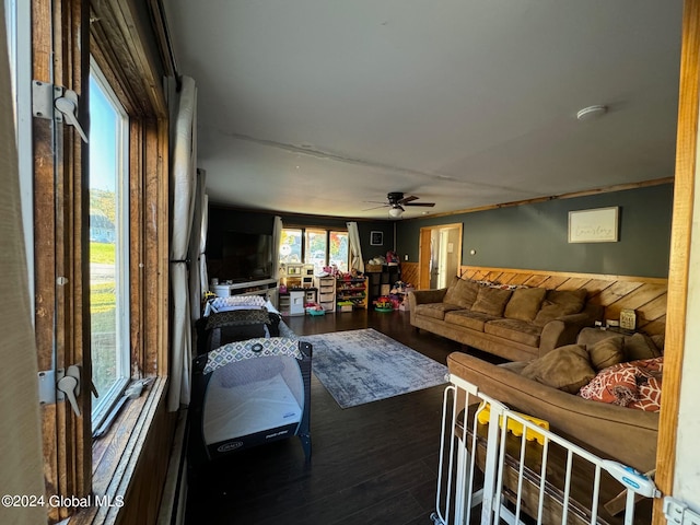 living room featuring wood walls, dark wood-type flooring, and ceiling fan