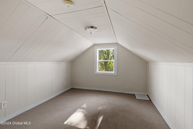 additional living space with carpet, vaulted ceiling, and wooden walls