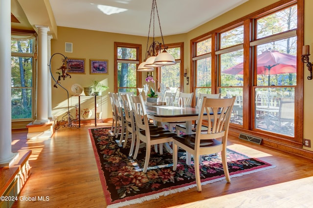 dining space featuring decorative columns, light hardwood / wood-style floors, and plenty of natural light