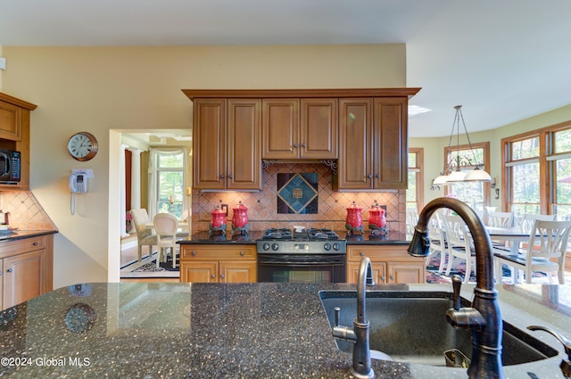 kitchen with dark stone countertops, a healthy amount of sunlight, black appliances, and decorative backsplash