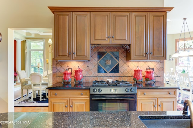 kitchen featuring black gas range, pendant lighting, wood-type flooring, and dark stone countertops