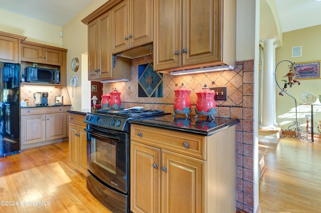 kitchen featuring ornate columns, light hardwood / wood-style flooring, dark stone counters, black appliances, and tasteful backsplash