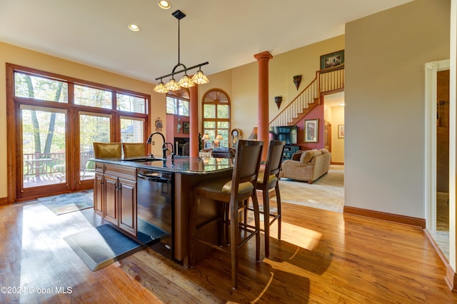 kitchen featuring light hardwood / wood-style flooring, dishwasher, a kitchen bar, and a center island with sink