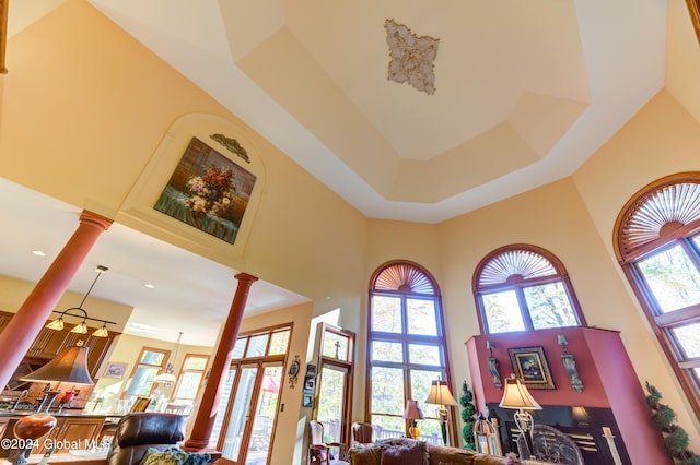 living room featuring decorative columns, a high ceiling, and a raised ceiling