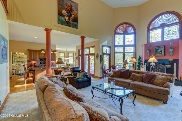 living room with light hardwood / wood-style floors, decorative columns, and a high ceiling