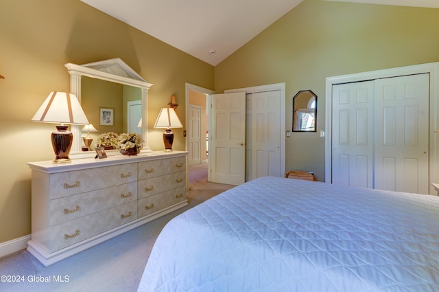 bedroom with light carpet, two closets, and high vaulted ceiling