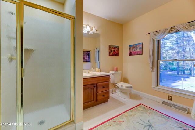 bathroom featuring vanity, a shower with shower door, toilet, and tile patterned floors