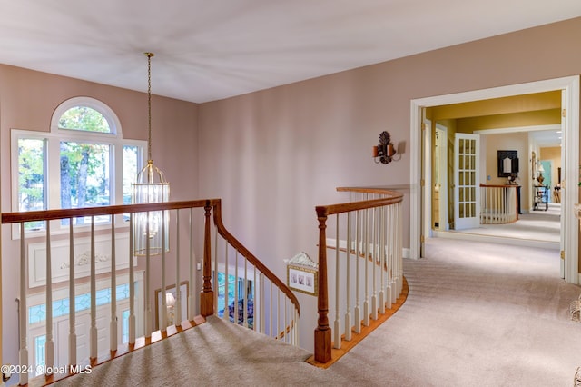 hall featuring carpet and a chandelier