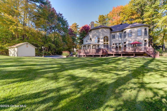 rear view of property with a storage unit, a deck, and a lawn