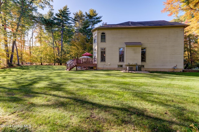 rear view of house featuring a deck, a lawn, and cooling unit