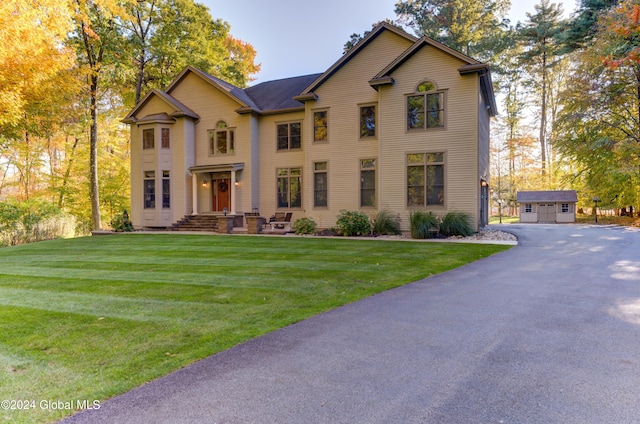 view of front facade featuring a front yard, a garage, and an outbuilding