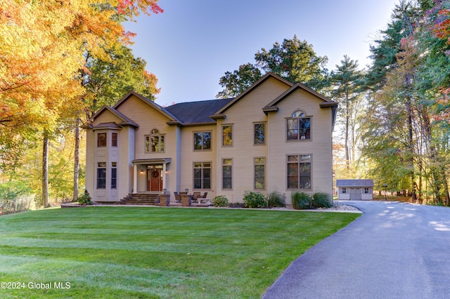 view of front facade featuring a garage, a front lawn, and an outdoor structure