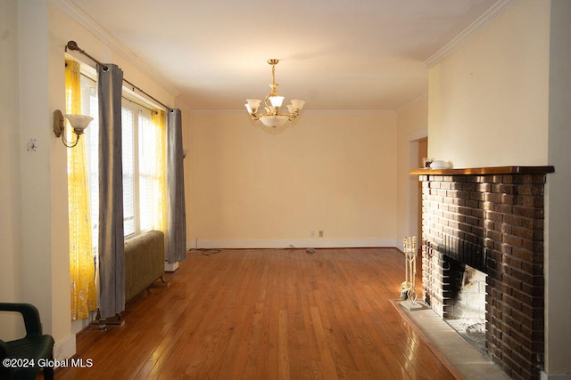 interior space featuring radiator heating unit, an inviting chandelier, wood-type flooring, a brick fireplace, and crown molding