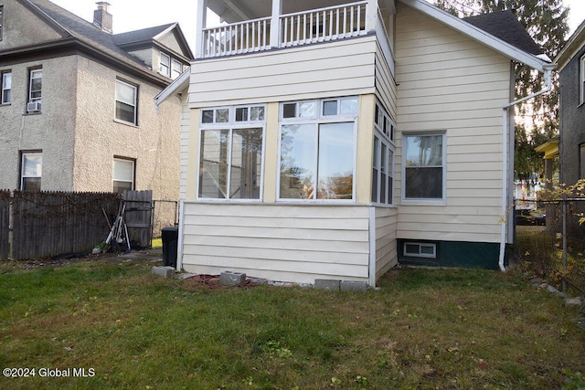 back of property with a balcony and a lawn