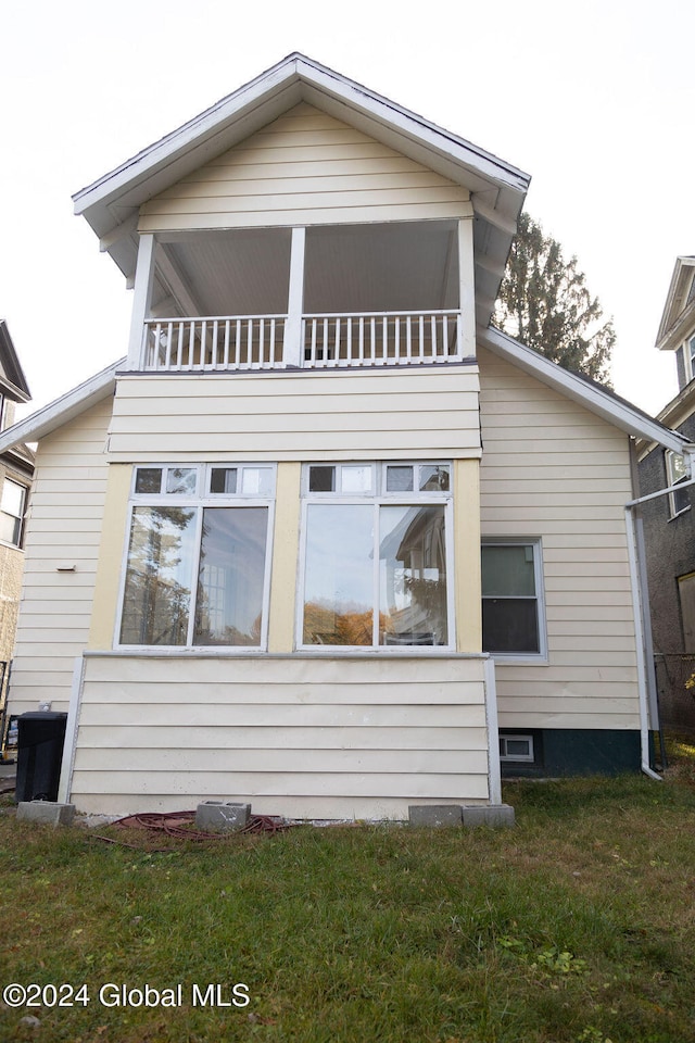 rear view of property with a yard and a balcony