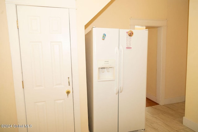 room details with white refrigerator with ice dispenser and light wood-type flooring