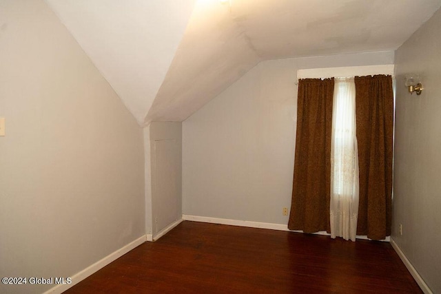 additional living space featuring wood finished floors, vaulted ceiling, and baseboards