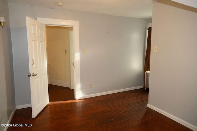 spare room featuring dark hardwood / wood-style floors and radiator heating unit