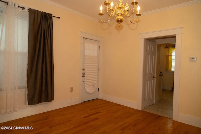 empty room featuring an inviting chandelier, crown molding, and hardwood / wood-style flooring