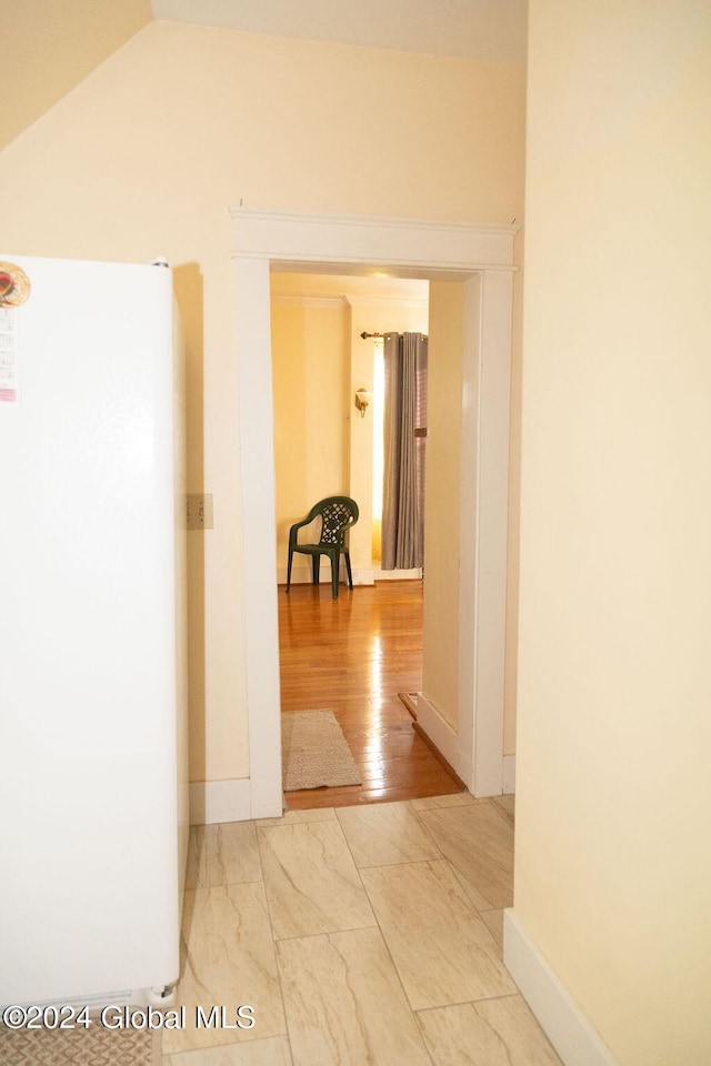 hallway featuring marble look tile flooring, vaulted ceiling, and baseboards