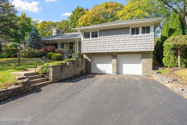 tri-level home featuring a garage, driveway, a chimney, and stairs