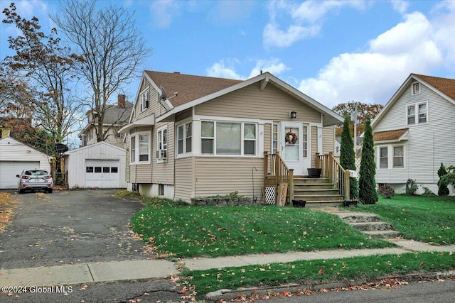 bungalow featuring a garage, a front lawn, and an outbuilding