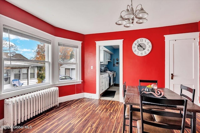 dining room with dark wood-type flooring, a notable chandelier, and radiator heating unit