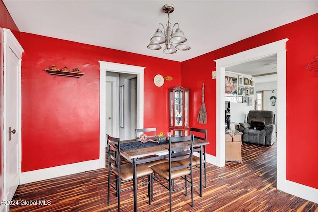 dining area featuring dark wood-type flooring and an inviting chandelier