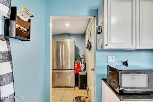 kitchen with white cabinets, light tile patterned floors, and stainless steel refrigerator