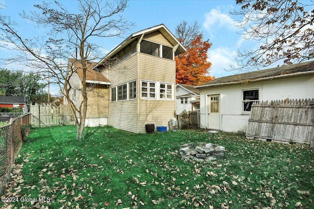 back of house featuring a fire pit and a lawn