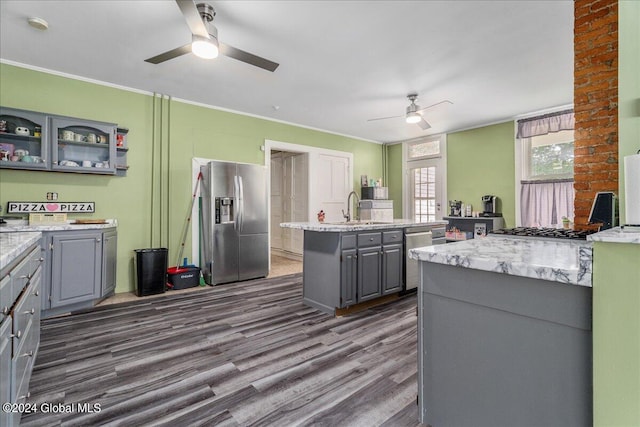 kitchen with gray cabinetry, a kitchen island with sink, dark hardwood / wood-style floors, ornamental molding, and appliances with stainless steel finishes