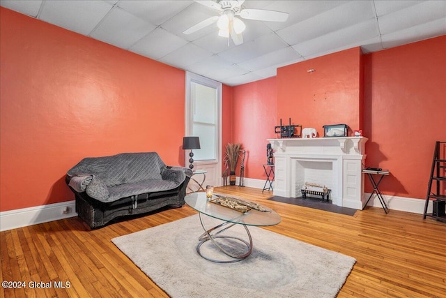 living room featuring a drop ceiling, ceiling fan, and wood-type flooring