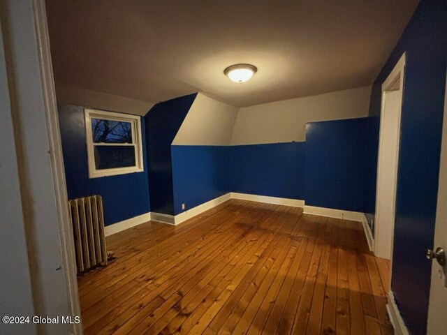 bonus room with radiator and hardwood / wood-style flooring