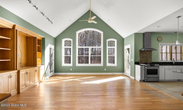 unfurnished living room featuring plenty of natural light, sink, light wood-type flooring, and ceiling fan