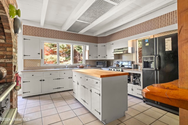 kitchen featuring wooden counters, beam ceiling, stainless steel appliances, ventilation hood, and white cabinets