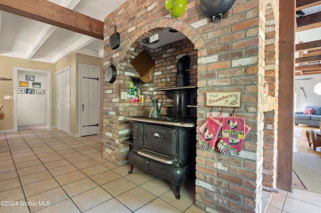 kitchen featuring beamed ceiling, light tile patterned floors, and a wood stove