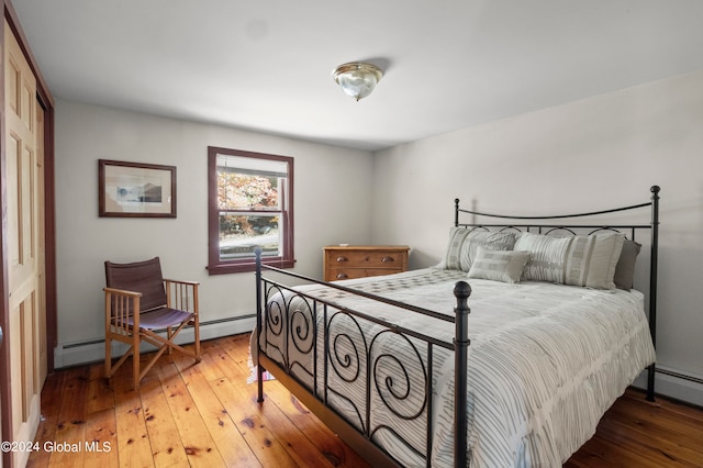 bedroom featuring baseboard heating, hardwood / wood-style flooring, and a closet