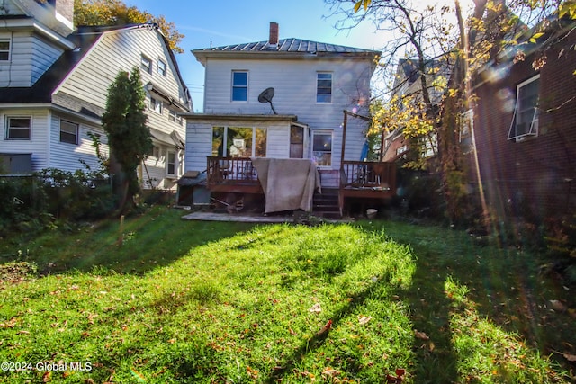 rear view of property featuring a wooden deck and a lawn