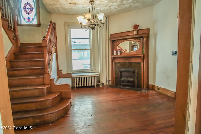 unfurnished room with a notable chandelier, a textured ceiling, radiator, and dark hardwood / wood-style flooring