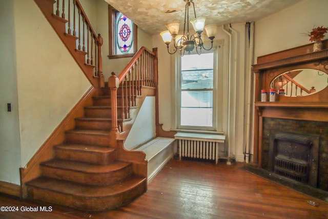 stairs featuring radiator, hardwood / wood-style flooring, and an inviting chandelier