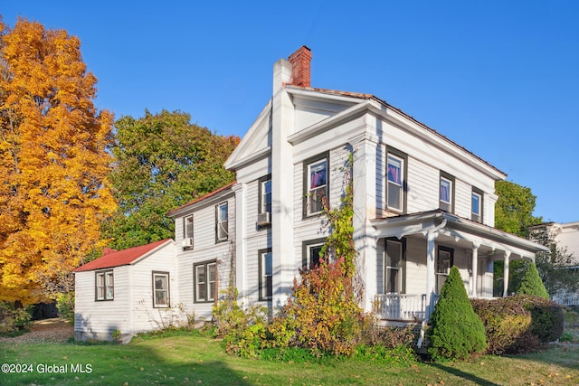 view of side of property featuring a porch and a lawn