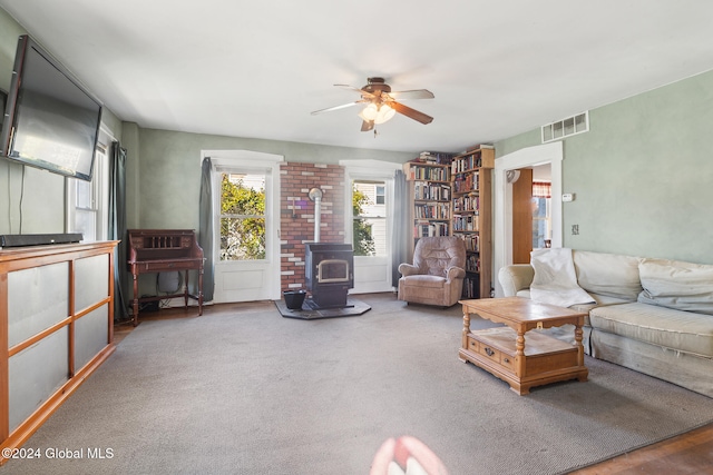 carpeted living room with ceiling fan and a wood stove