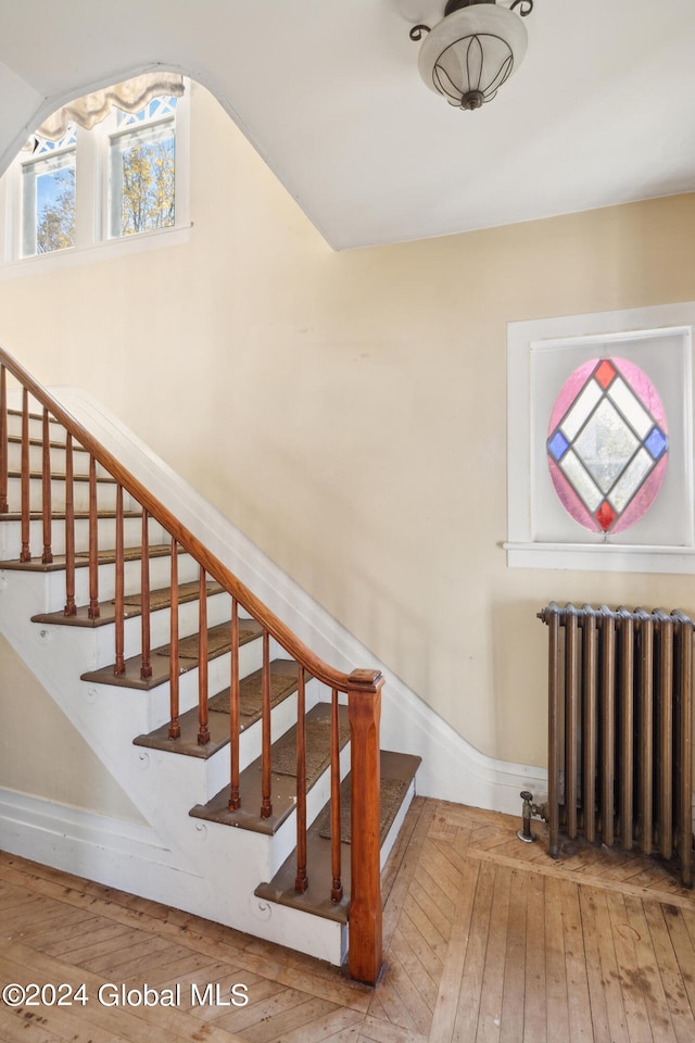 stairs featuring radiator and hardwood / wood-style floors