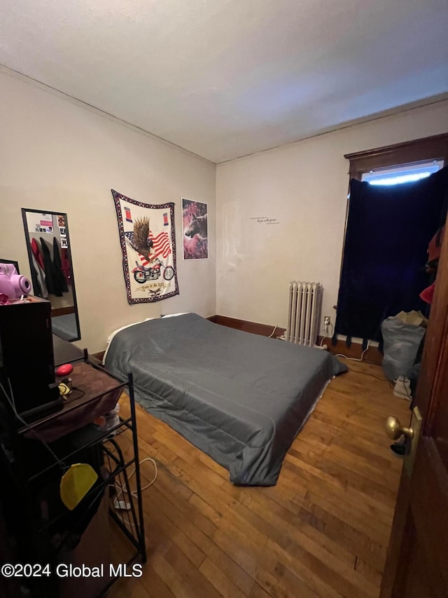 bedroom featuring radiator heating unit and wood-type flooring